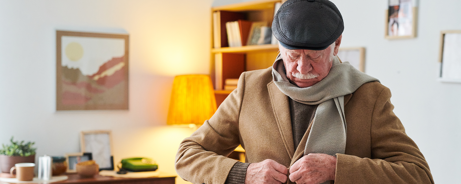 An older man getting his coat buttoned in his living room
