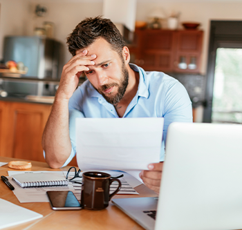 Man with hand on his head and looking at a document looking stressed