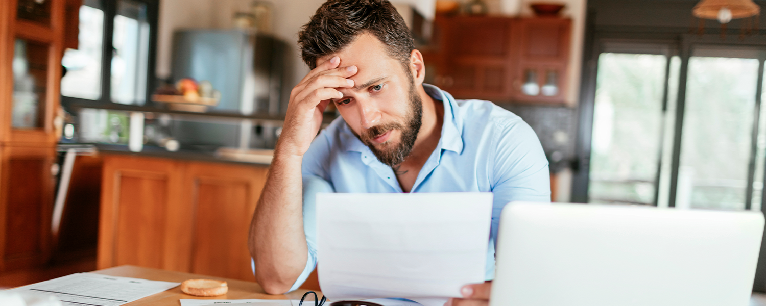Man with hand on his head and looking at a document looking stressed