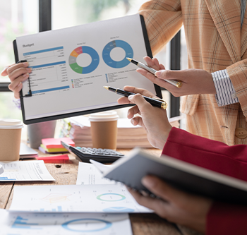 Hands of two people point with a pen at a chart