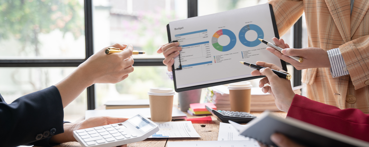 Hands of three people point with a pen at a chart